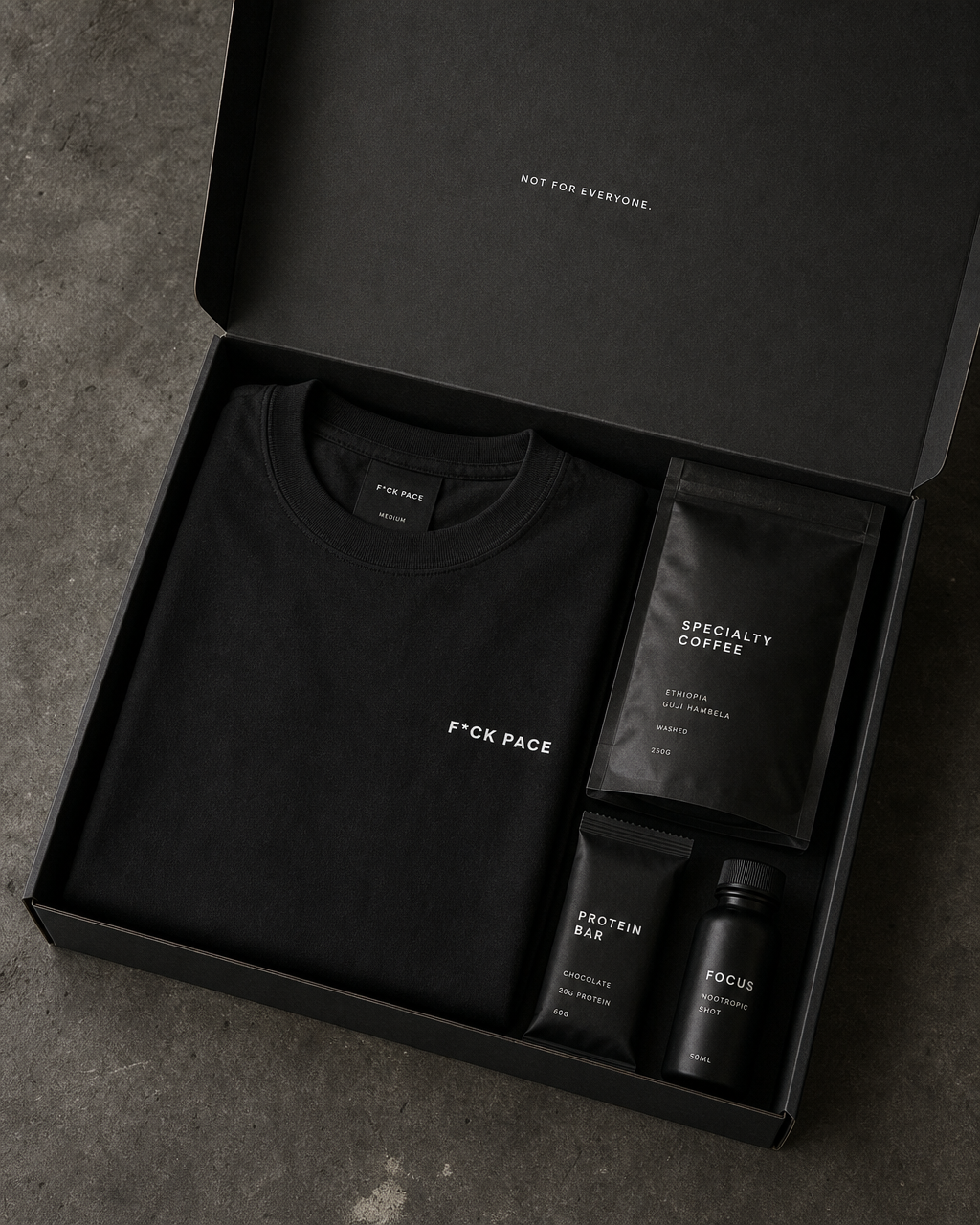 Kit F*CK PACE em caixa preta com a camiseta dobrada mostrando a frente, café especial, barra de proteína e shot